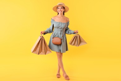 Photo of Smiling woman with shopping bags on yellow background