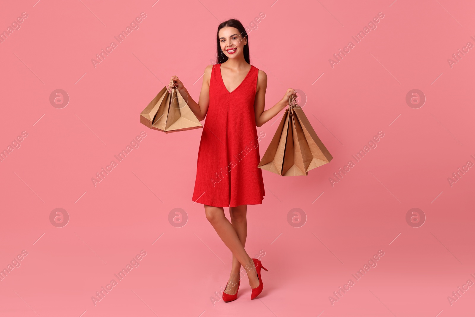 Photo of Smiling woman with shopping bags on pink background