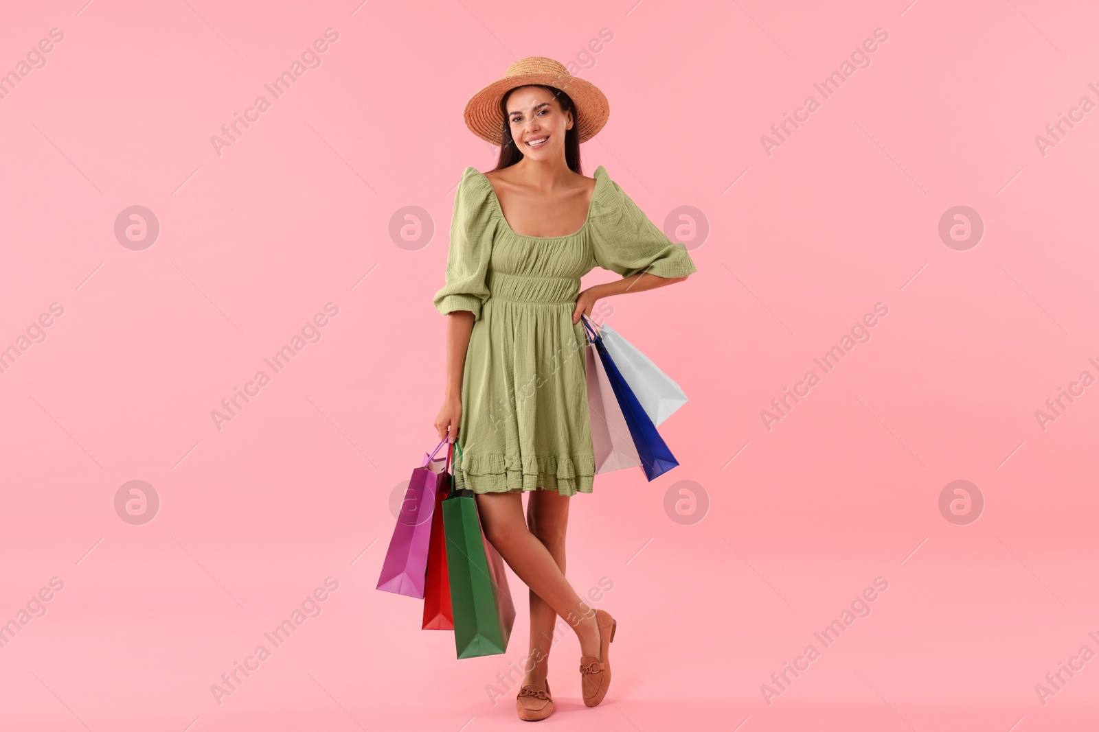 Photo of Smiling woman with colorful shopping bags on pink background