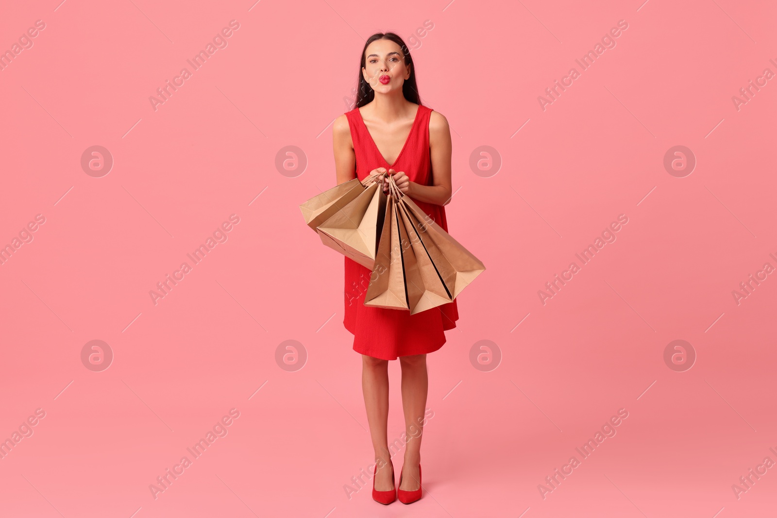 Photo of Beautiful woman with shopping bags on pink background