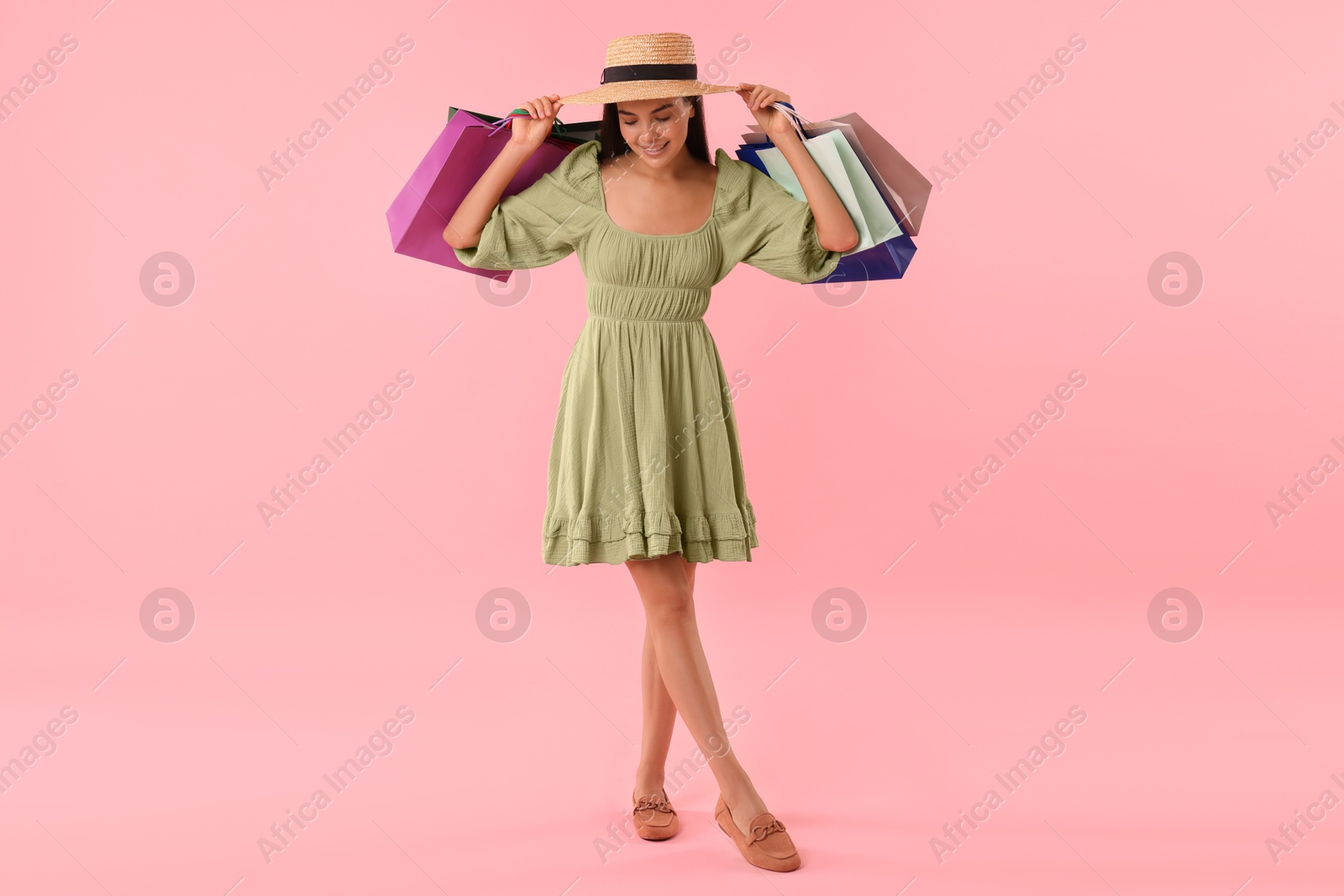 Photo of Smiling woman with colorful shopping bags on pink background