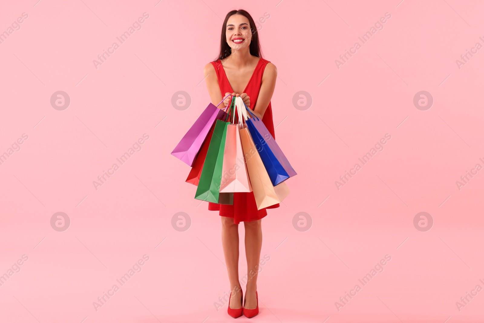 Photo of Smiling woman with colorful shopping bags on pink background