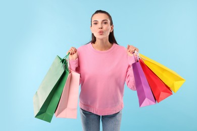 Photo of Beautiful woman with colorful shopping bags on light blue background