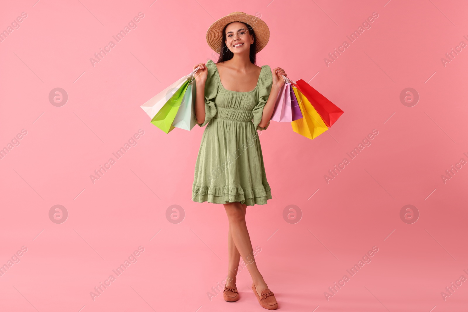 Photo of Smiling woman with colorful shopping bags on pink background