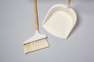 Photo of Cleaning broom and dustpan on grey background, flat lay