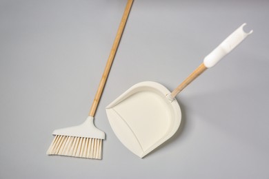 Photo of Cleaning broom and dustpan on grey background, flat lay