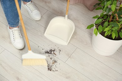 Photo of Woman with broom and dustpan cleaning floor indoors, closeup