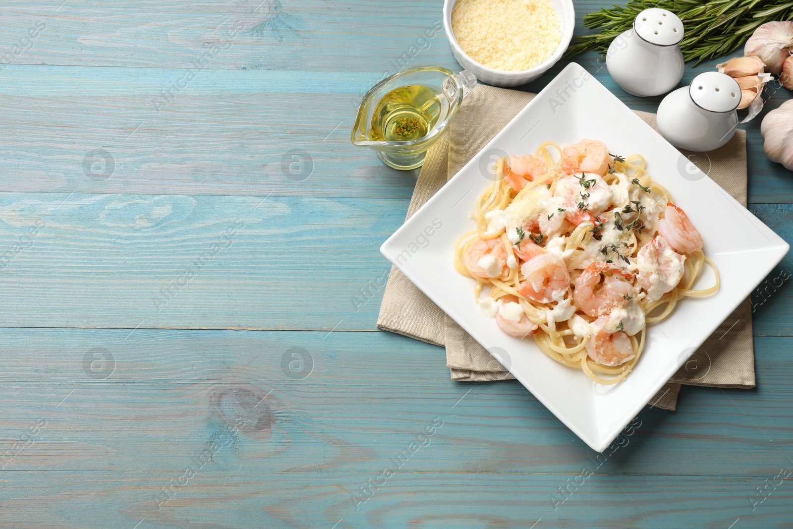 Photo of Delicious pasta with shrimps served on blue wooden table, flat lay. Space for text