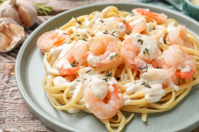 Photo of Delicious pasta with shrimps served on wooden table, closeup