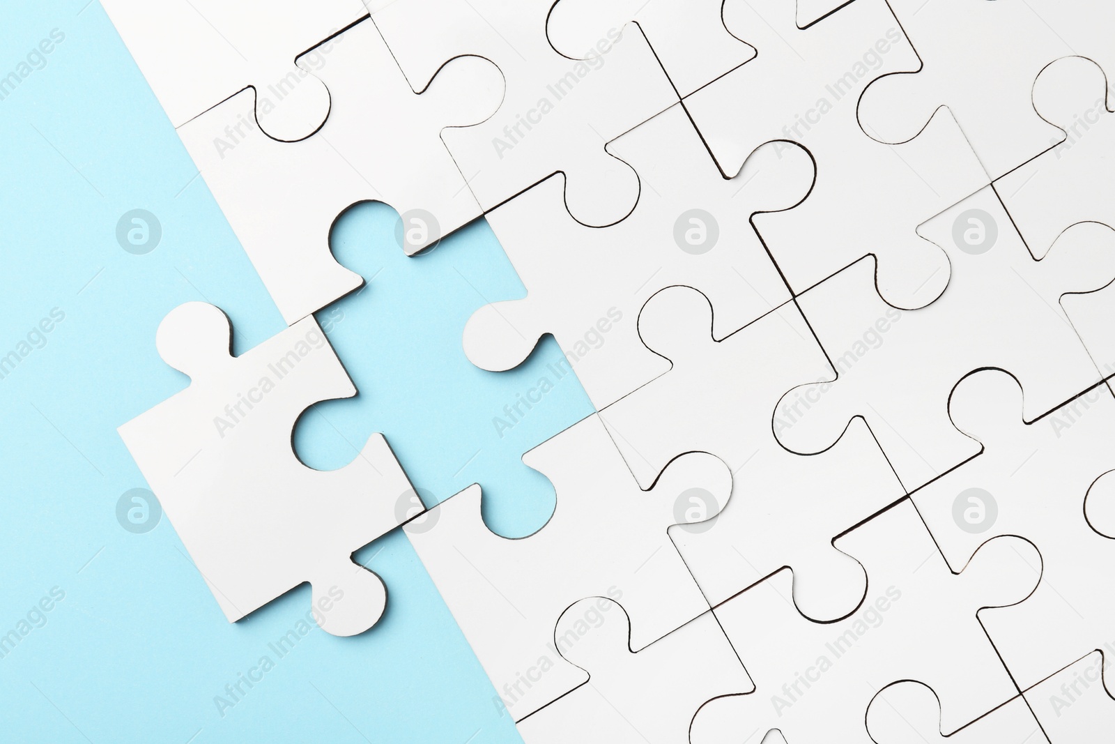 Photo of White puzzle pieces on light blue background, top view