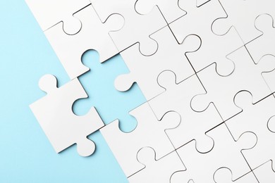 Photo of White puzzle pieces on light blue background, top view