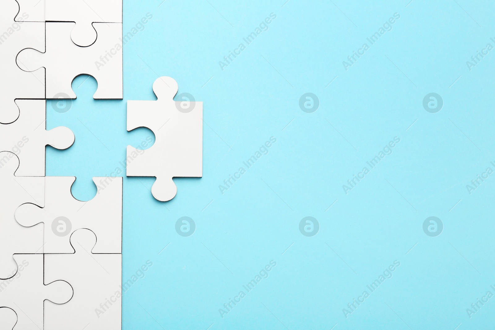 Photo of White puzzle pieces on light blue background, top view. Space for text