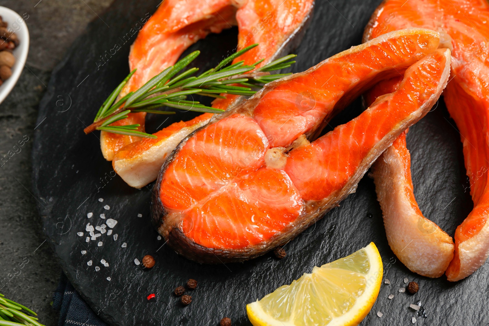 Photo of Tasty grilled salmon steaks, lemon and spices on gray table, top view