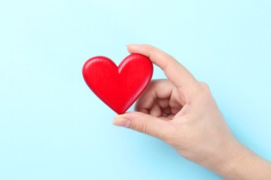 Photo of Woman with red heart on light blue background, closeup