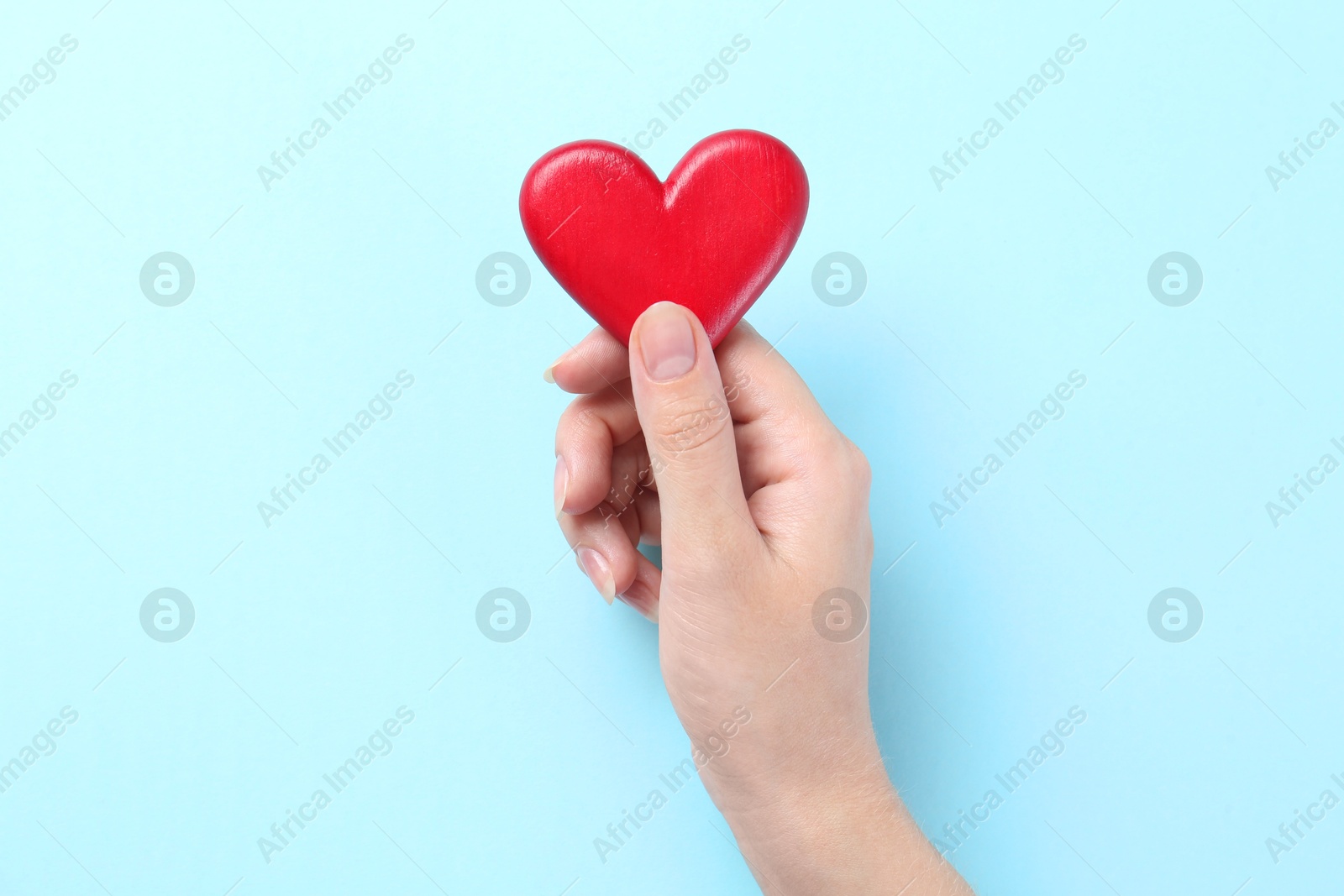 Photo of Woman with red heart on light blue background, closeup