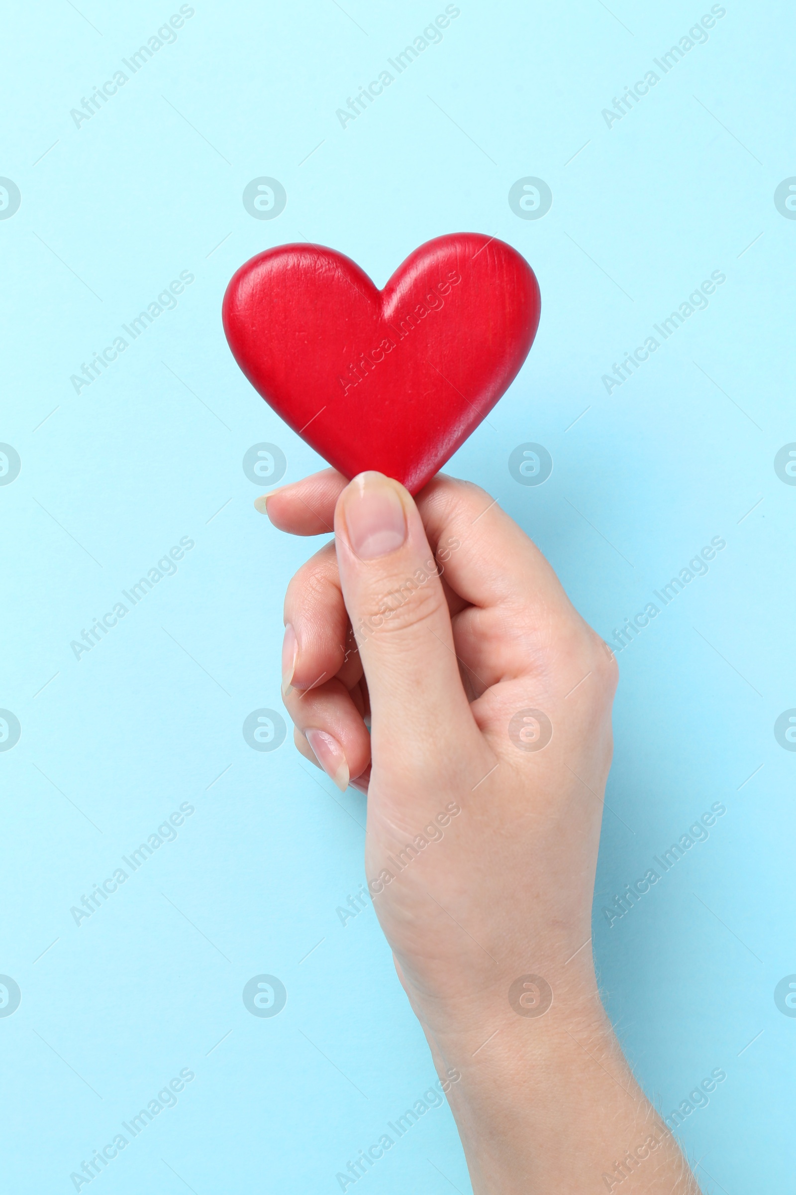 Photo of Woman with red heart on light blue background, closeup