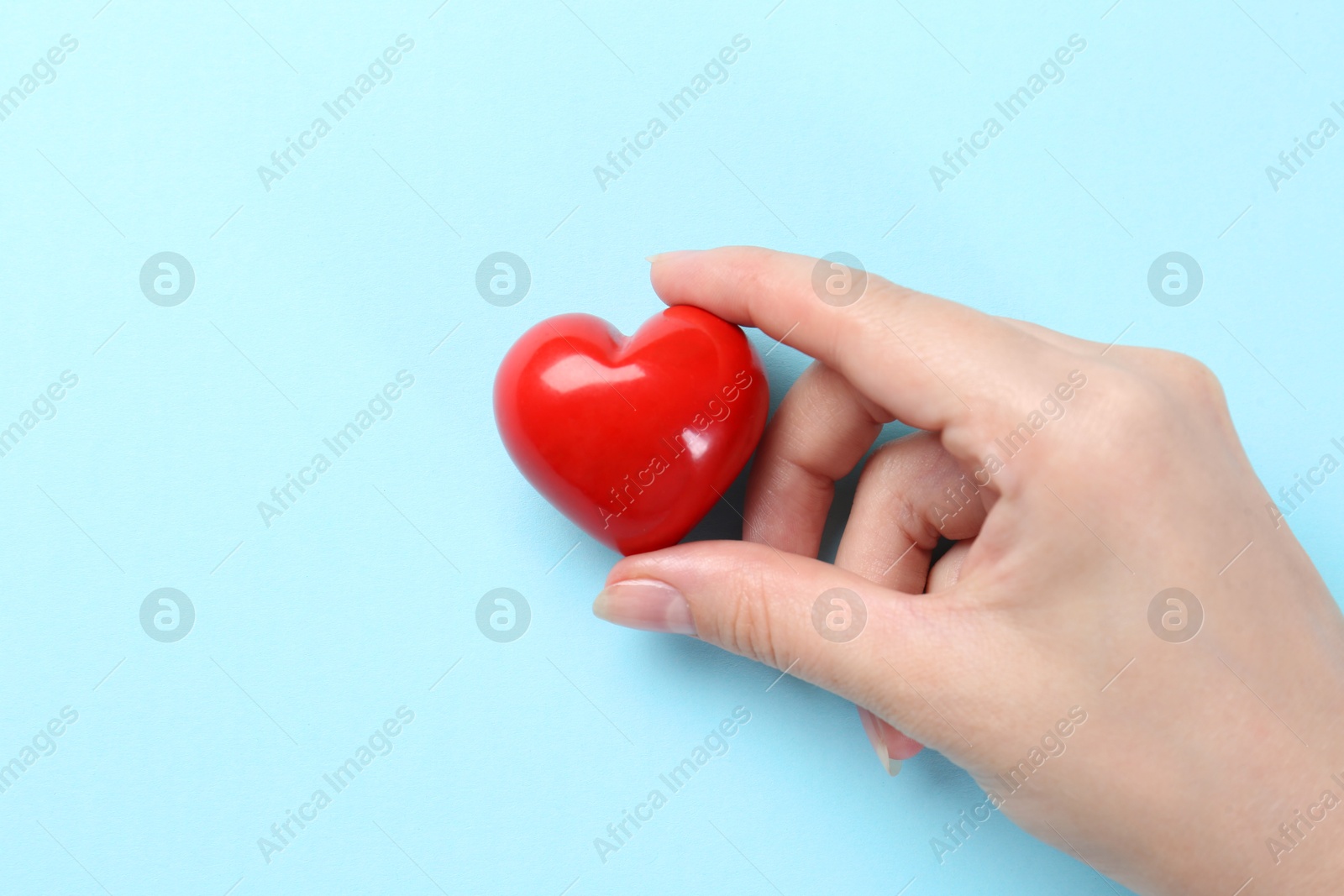 Photo of Woman with red heart on light blue background, closeup