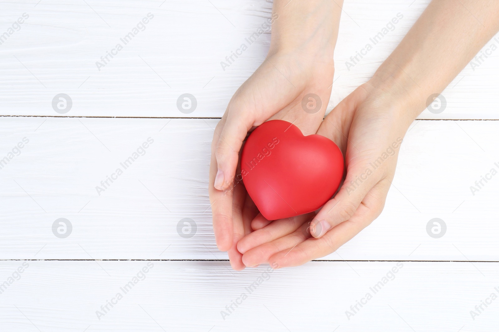 Photo of Woman holding red heart on white wooden background, top view. Space for text