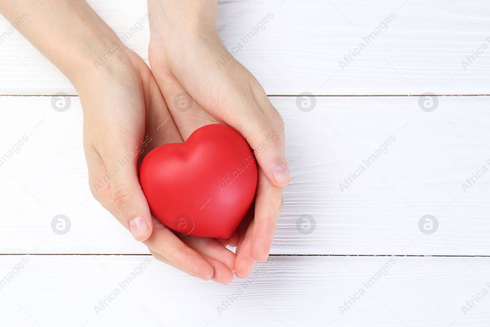 Photo of Woman holding red heart on white wooden background, top view. Space for text