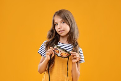 Cute girl with carnival mask on orange background