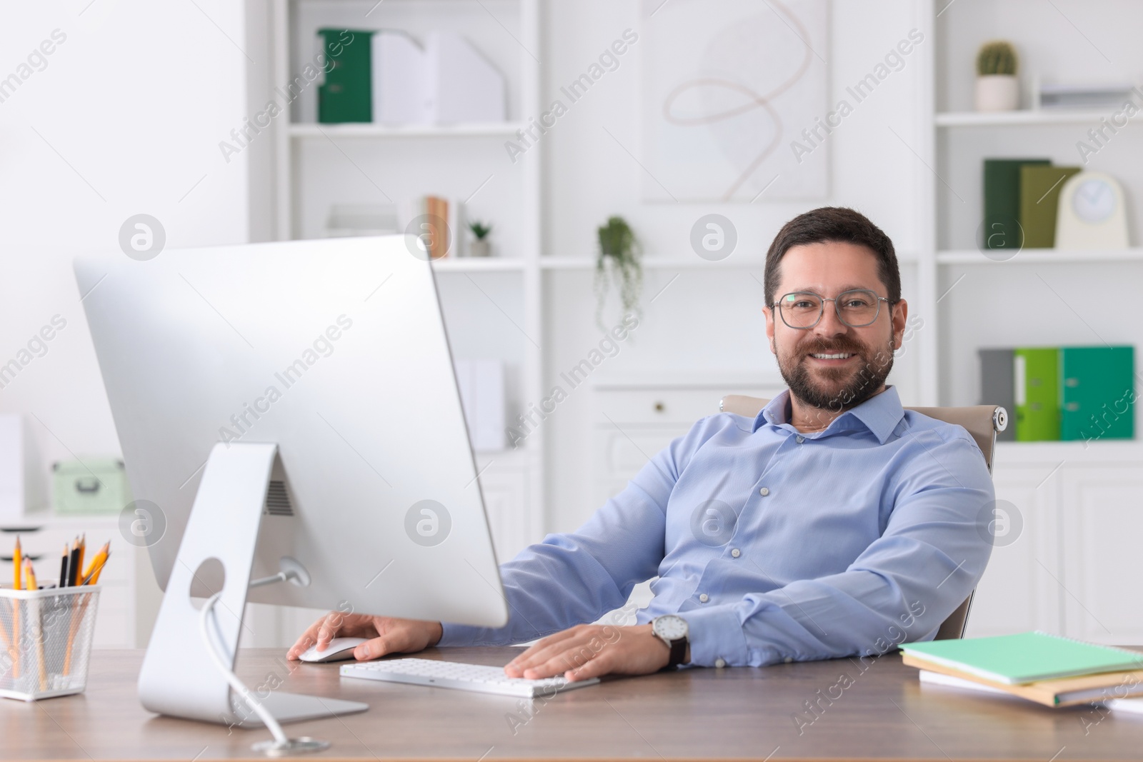 Photo of Smiling businessman working at table in office