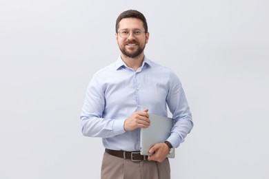 Portrait of smiling businessman with laptop on grey background