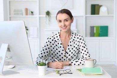 Photo of Smiling businesswoman working at table in office