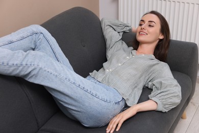 Photo of Smiling woman relaxing on sofa at home