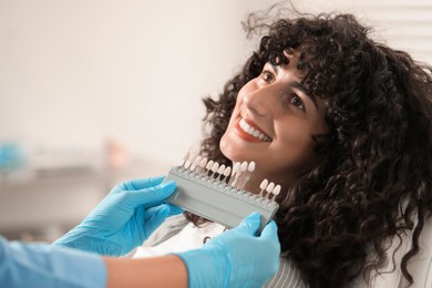 Photo of Doctor checking young woman's teeth color in clinic, closeup. Dental veneers