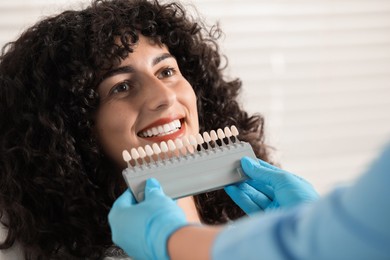 Doctor checking young woman's teeth color in clinic, closeup. Dental veneers