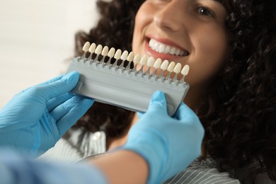 Photo of Doctor checking young woman's teeth color in clinic, closeup. Dental veneers