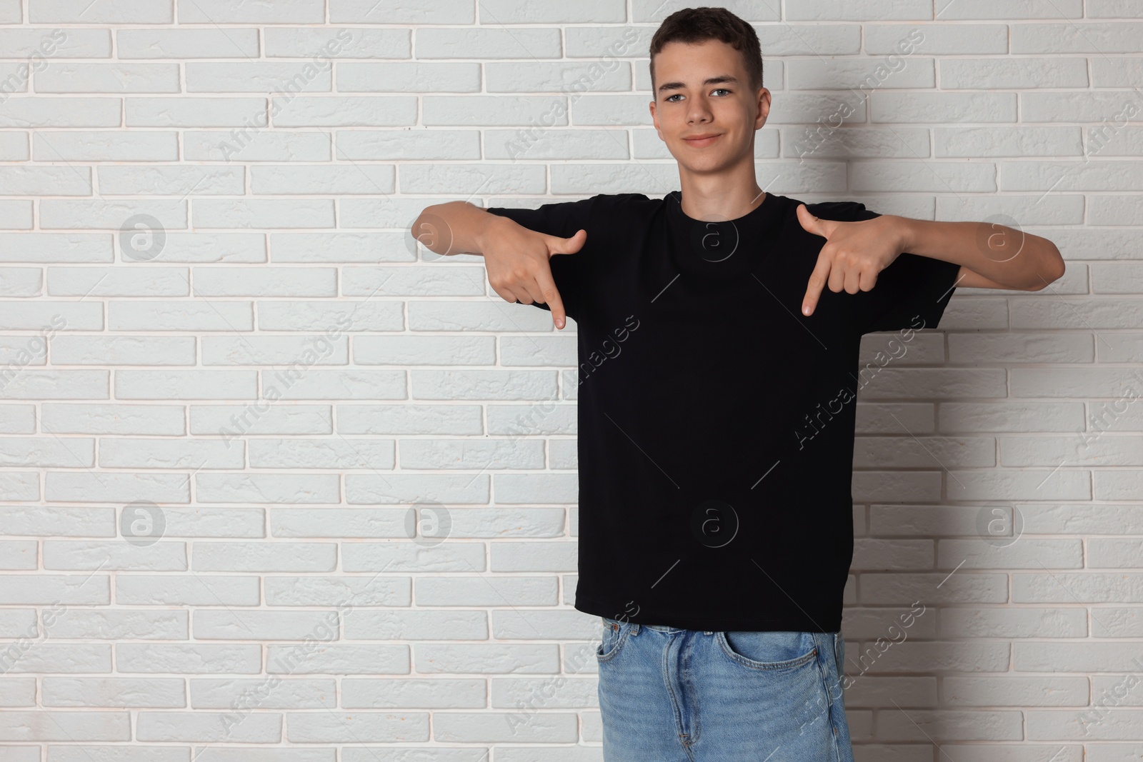 Photo of Teenage boy wearing black t-shirt near white brick wall, space for text