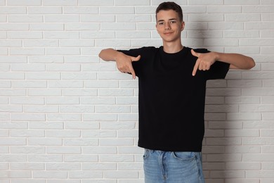 Photo of Teenage boy wearing black t-shirt near white brick wall, space for text