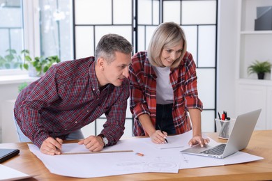 Photo of Architects making engineering drawing at wooden table in office