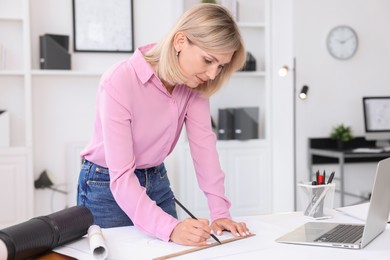 Photo of Architect making engineering drawing at table in office