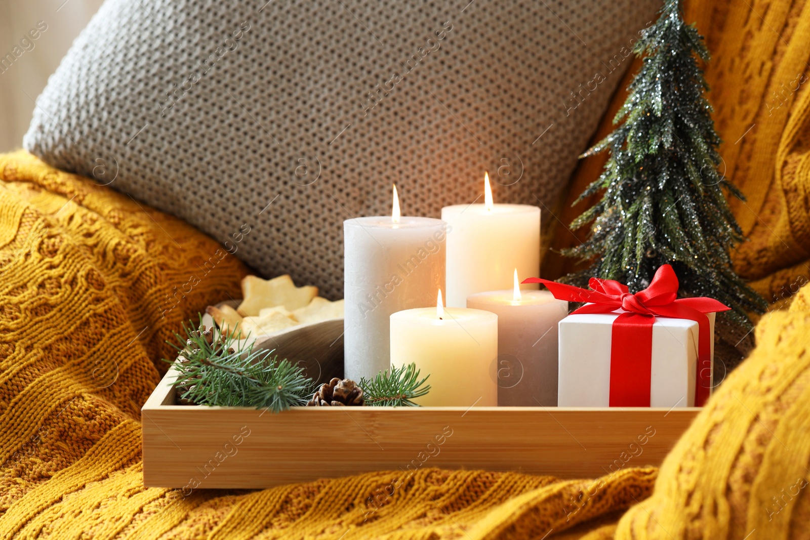 Photo of Tray with burning candles and Christmas decor on armchair