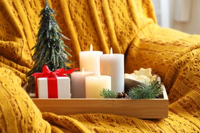 Photo of Tray with burning candles and Christmas decor on armchair