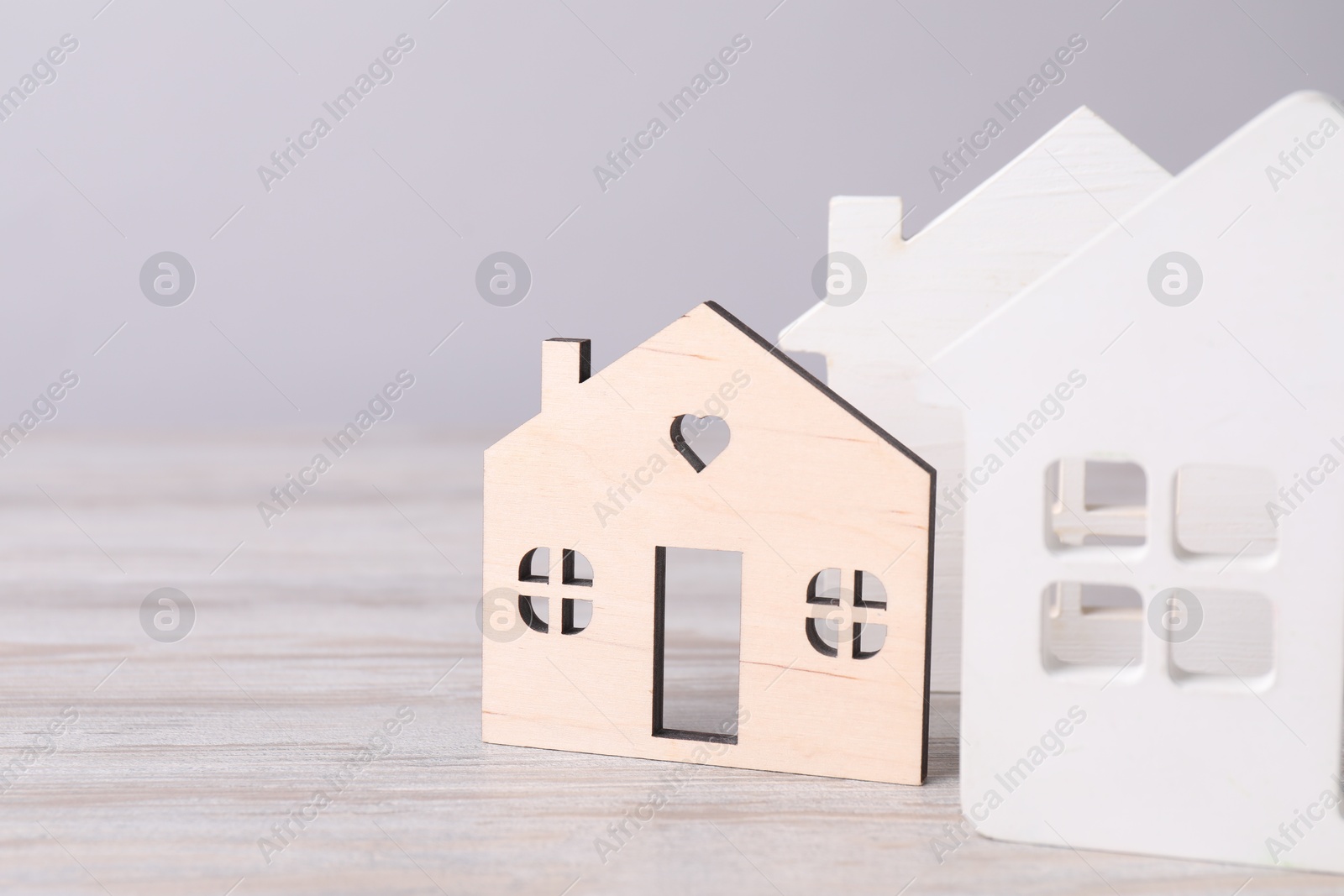 Photo of House hunting. House figures on wooden table. Space for text