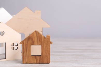 House hunting. House figures on wooden table. Space for text