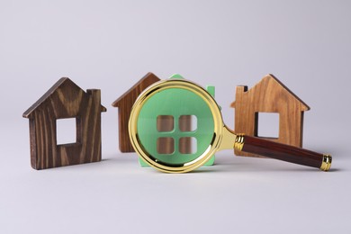 House hunting. Magnifying glass and house figures on grey background