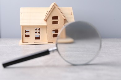 Photo of House hunting. Magnifying glass and house model on grey background