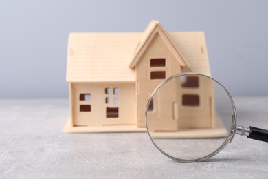 Photo of House hunting. Magnifying glass and house model on grey background