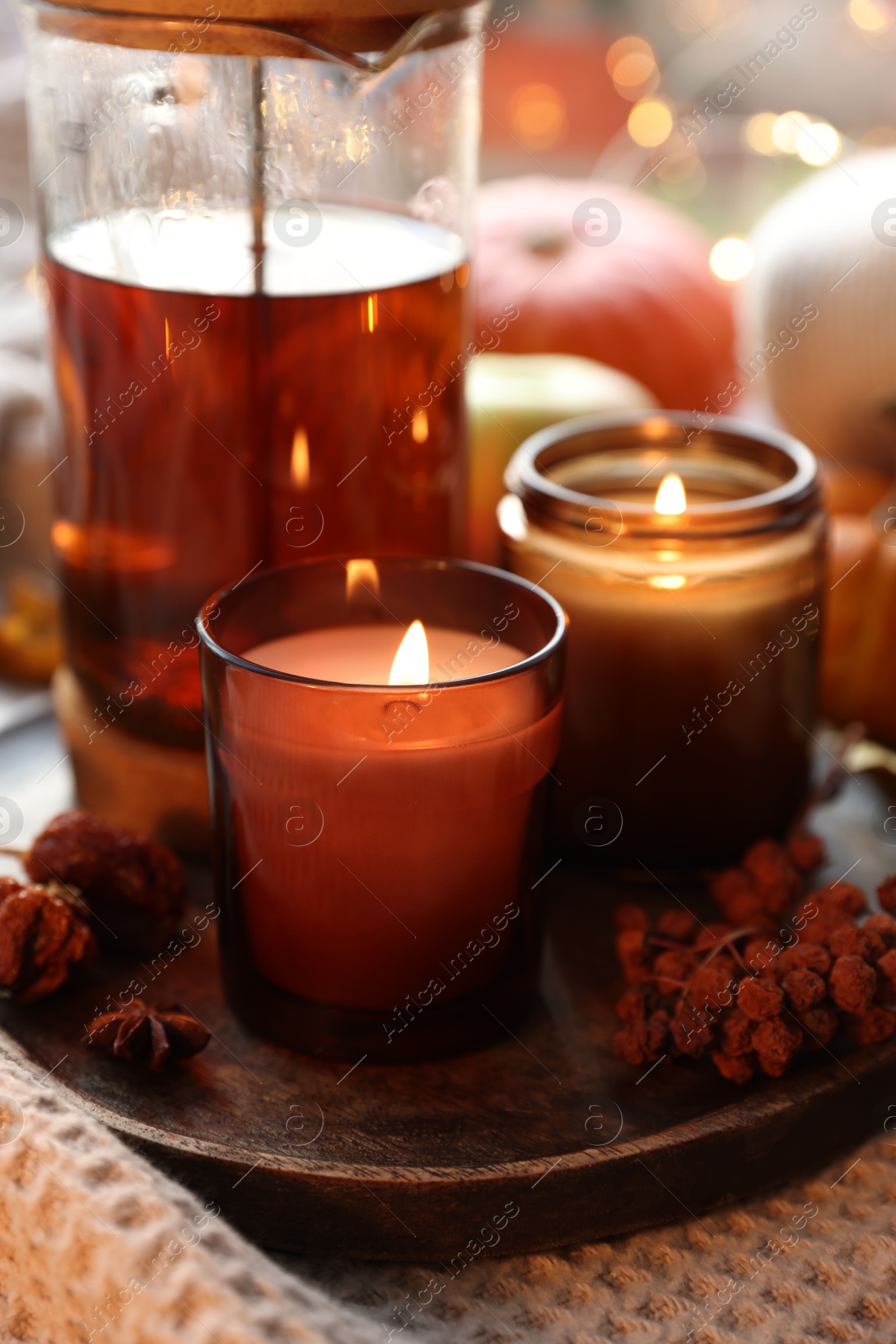 Photo of Burning candles, freshly brewed tea and autumn decor on fabric, closeup