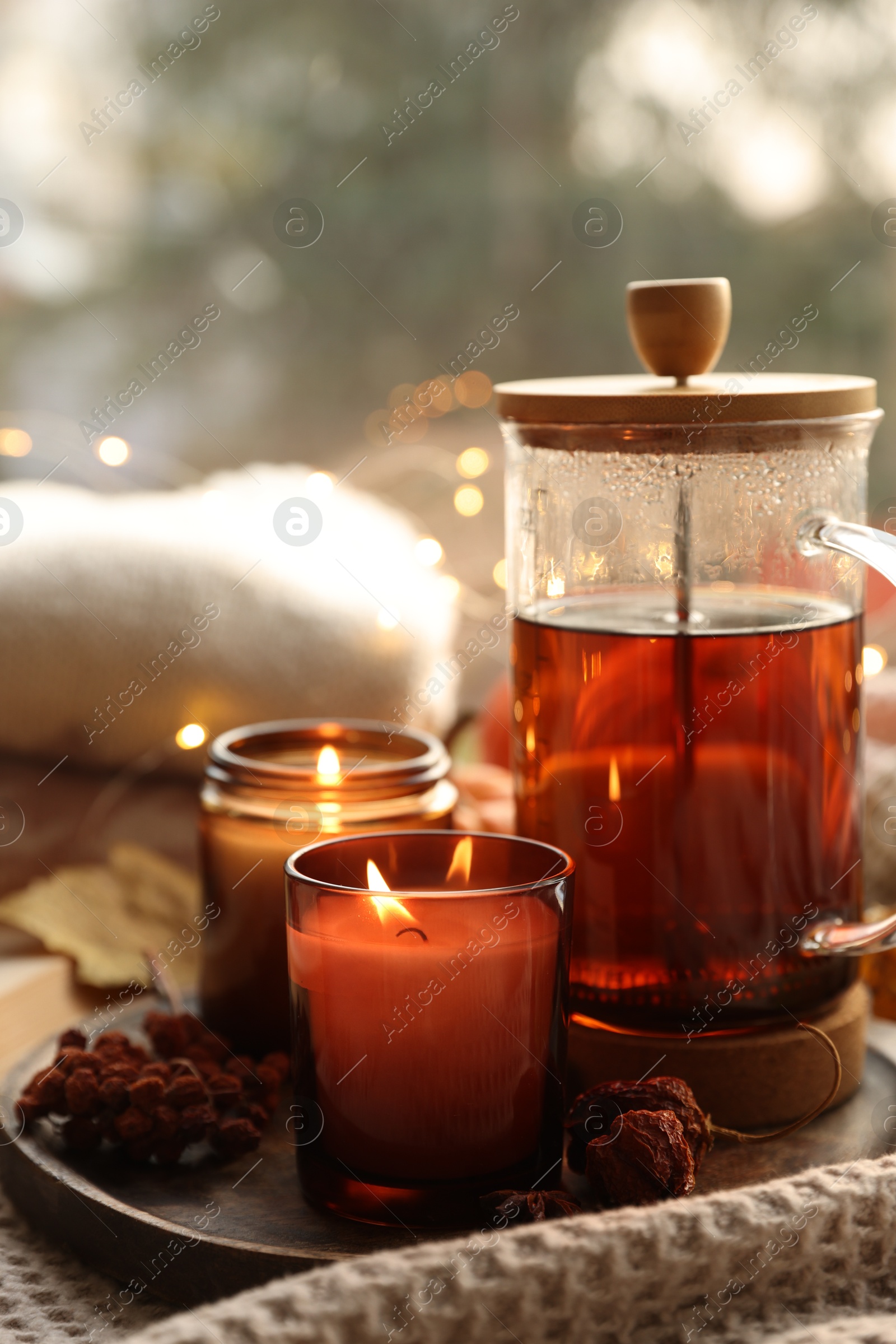 Photo of Burning candles, freshly brewed tea and autumn decor on fabric