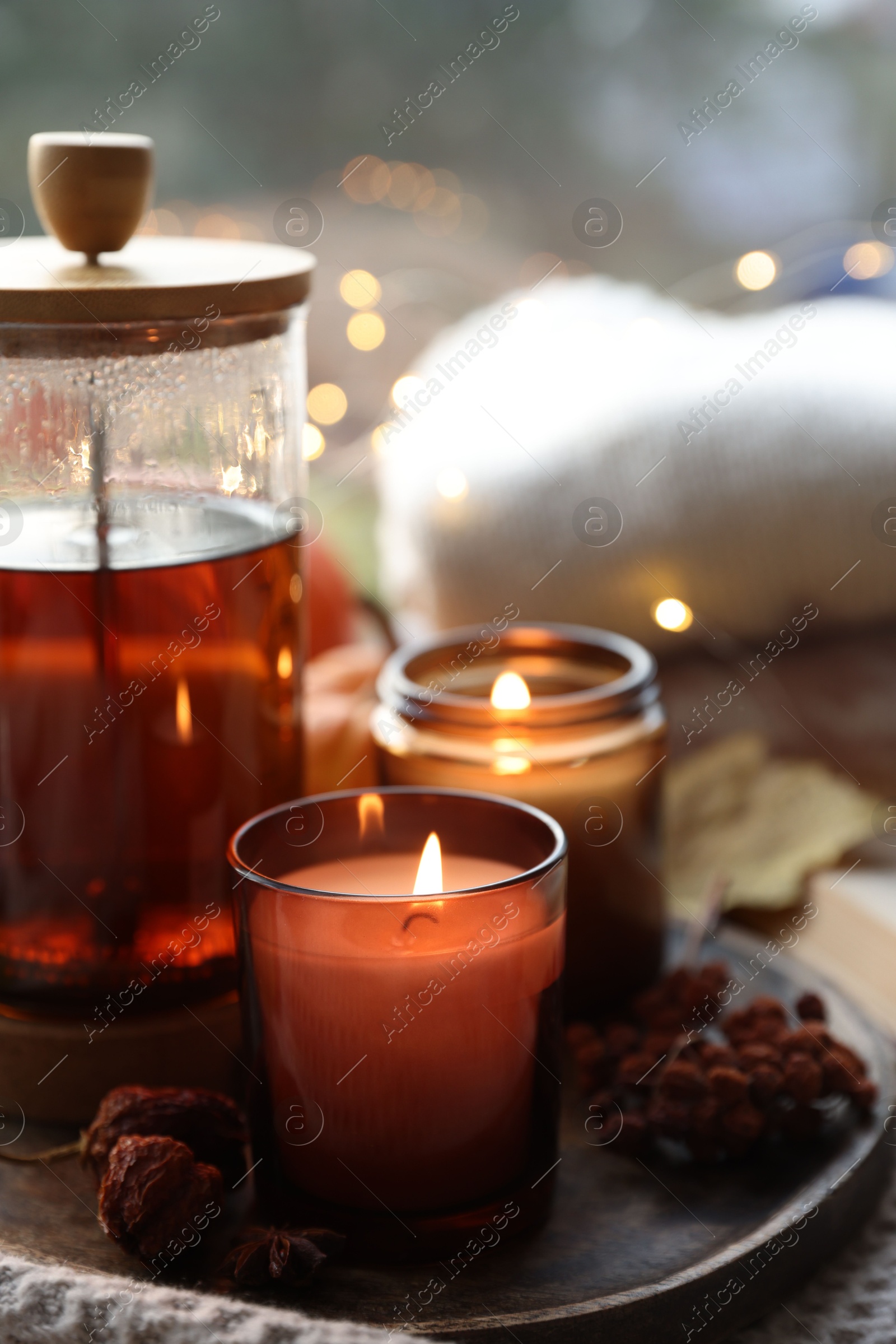 Photo of Burning candles, freshly brewed tea and autumn decor on fabric, closeup