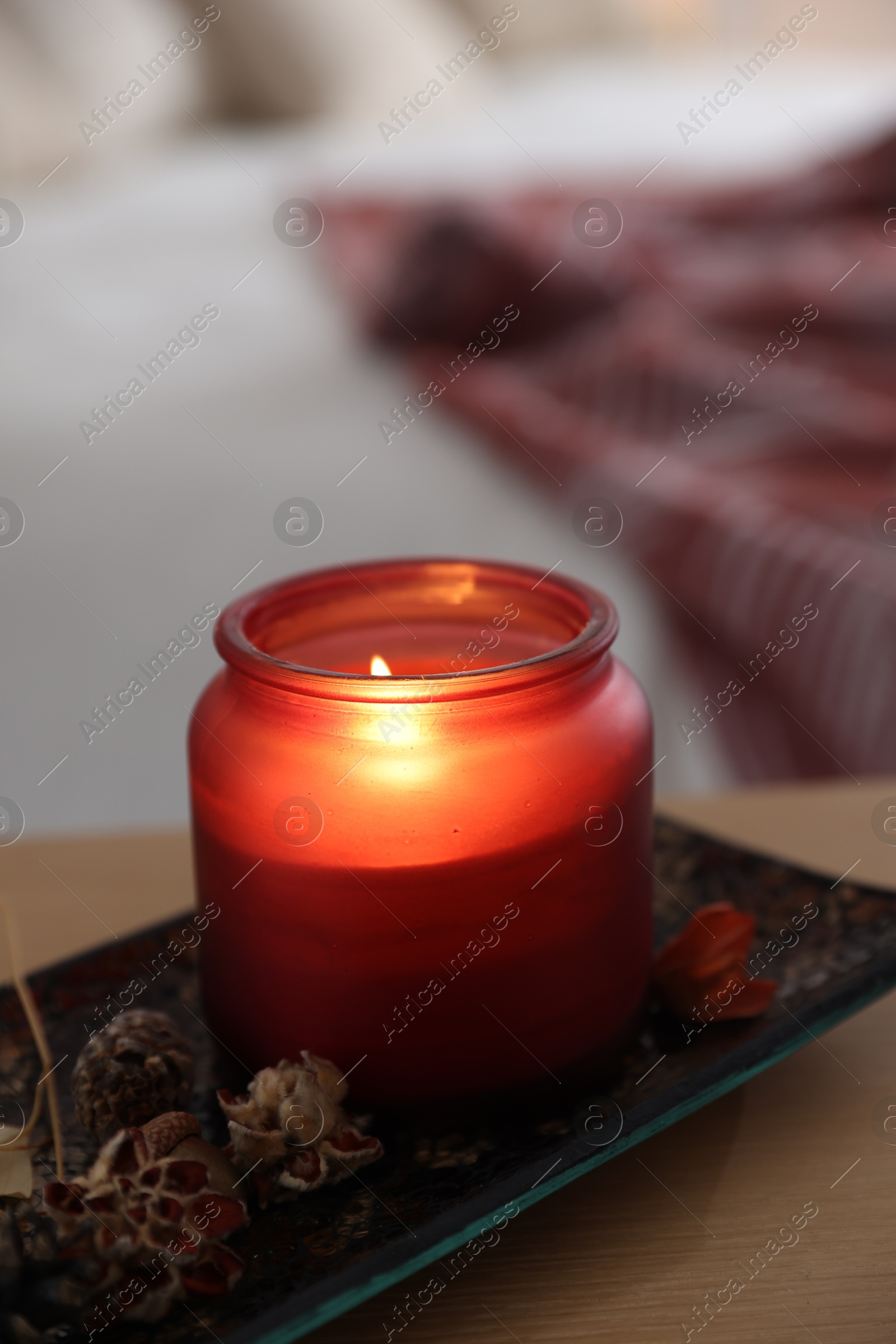 Photo of Burning candle and dry flowers on wooden table indoors, closeup. Autumn atmosphere