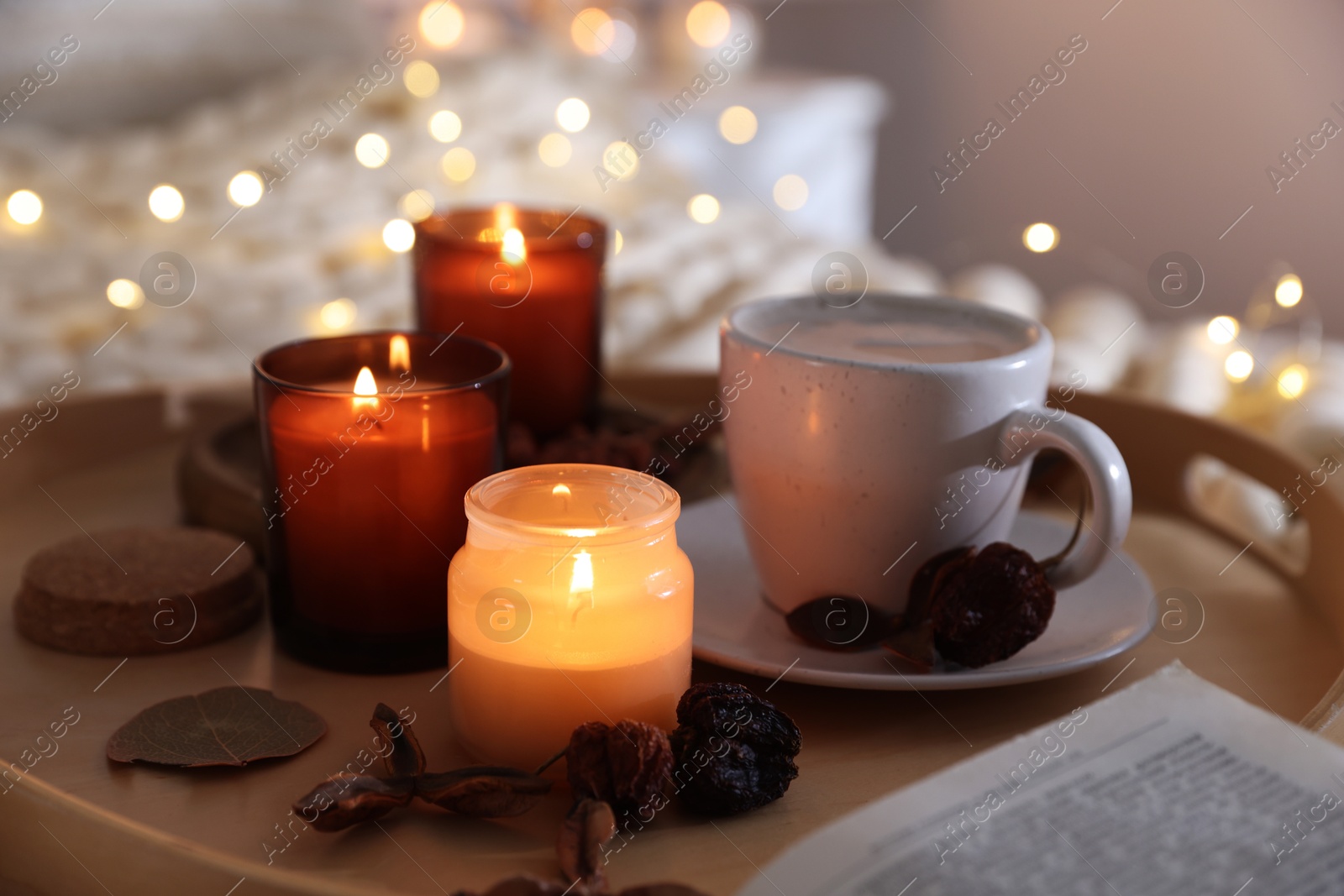 Photo of Burning candles, lights, coffee and decor on bed indoors, closeup. Autumn atmosphere