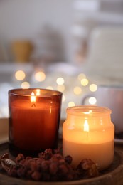 Photo of Burning candles and decor on tray indoors, closeup. Autumn atmosphere