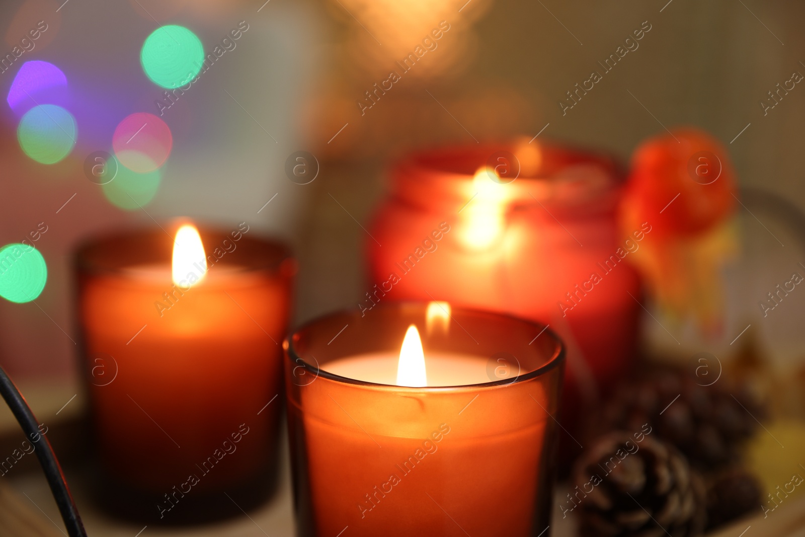 Photo of Burning candles and cone on table, closeup. Autumn atmosphere