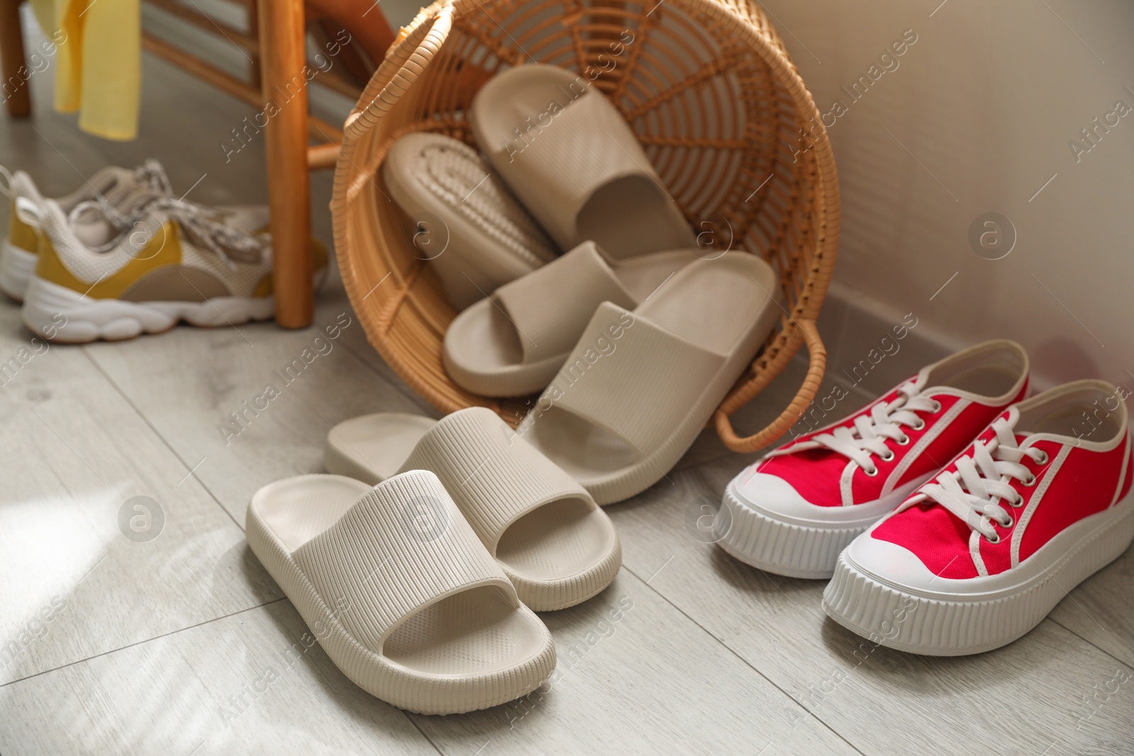 Photo of Basket with slippers for guests and sneakers in entryway at home